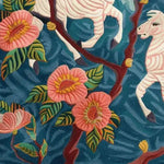 A vibrant hand-tufted area rug featuring a lively floral design with pink blossoms and green leaves on a rich blue background. The wool rug showcases intricate details, perfect for adding a touch of elegance to living room spaces. Ideal as an 8x10 living room rug, this floral rug combines beauty and functionality.