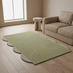 Green rug on a wooden floor with a beige sofa and small table in a room with large windows.