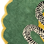 Scalloped green edge and gold border of the snake rug with part of the black-and-white serpent