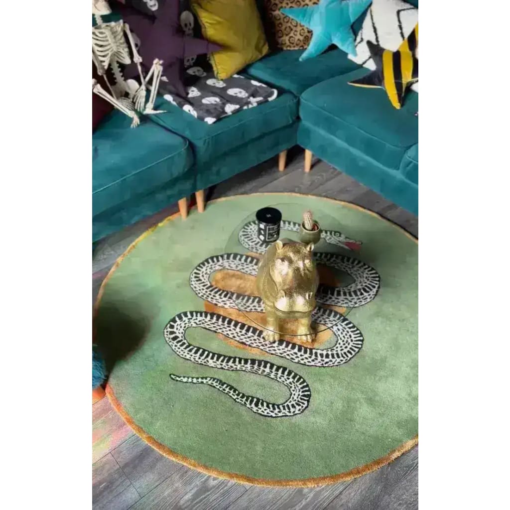 A stylish round wool rug in dark green featuring a scalloped snake design, perfect for adding a unique touch to dining rooms or bedrooms. The rug is placed in a cozy living space with teal couches and vibrant pillows, showcasing its versatility as an area rug.