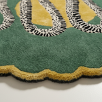 Close-up of a green rug with decorative patterns on a white background
