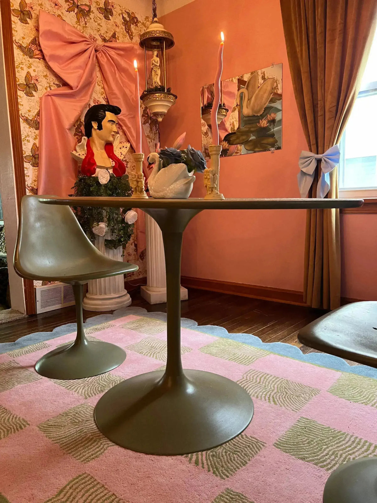 A stylish living room featuring a Scalloped Leaf Checker Pastel Hand Tufted Rug. This large area rug, perfect for a boho-inspired space, showcases a beautiful blend of pink and green checkered patterns with a scalloped border. The wool rug adds a cozy touch to the room, complementing the modern furniture and eclectic decor. Ideal for enhancing large living rooms with a touch of elegance and comfort.