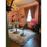 A charming living room featuring a Scalloped Leaf Checker Pastel Hand Tufted Rug, perfect for adding a touch of boho style. This wool area rug, with its soft pastel colors and unique scalloped edges, fits beautifully in large living room spaces. The rug complements the decor with its inviting texture, enhancing the warmth of the wooden floor and the room's cozy ambiance.