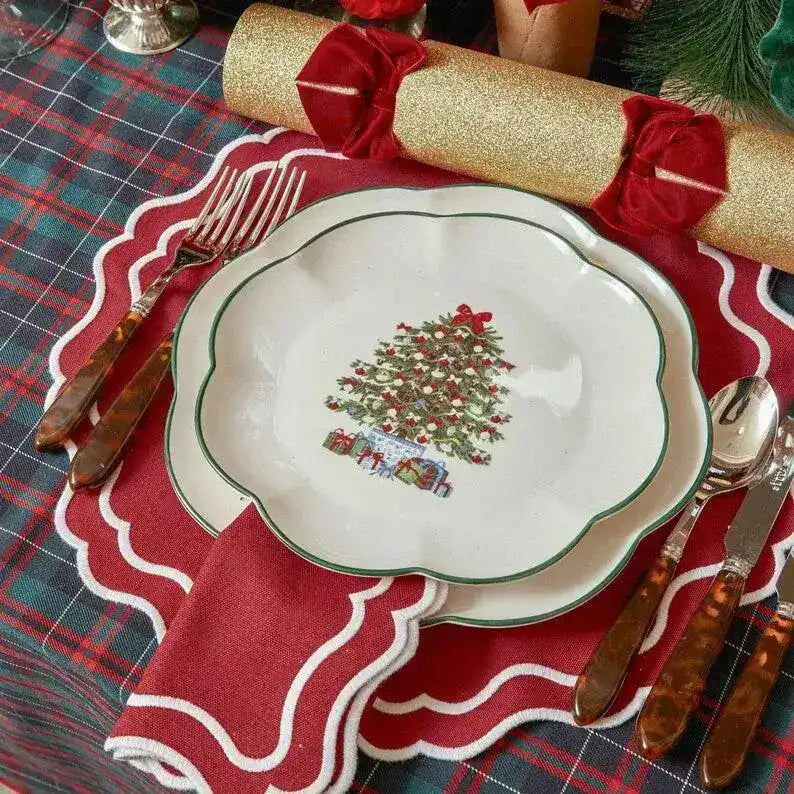 Scarlet scalloped placemat under a Christmas-tree plate with tortoiseshell flatware on plaid