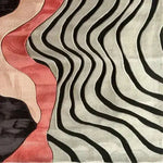 This sculptural hand-tufted area rug showcases a modern design with flowing black and white waves intermingling with soft pink and beige hues. Perfect for contemporary bedrooms and living rooms, this wool rug brings an artistic flair to any space, making it an ideal choice for those seeking unique bedroom area rugs.