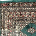 A detailed close-up of a Sea Green Sarong Hand Knotted Area Rug showcasing its intricate geometric patterns and rich colors, perfect for large living room rugs.