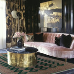 A stylish living room featuring a Sea Green Sarong Hand Knotted Area Rug with intricate patterns, complementing the plush pink sofa and modern gold coffee table. The large living room rug adds an elegant touch to the contemporary decor.