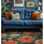 A vibrant living room scene featuring a Serene Garden Hand Tufted Area Rug with a striking floral design. The large 8x10 wool rug showcases vivid orange and white flowers against a rich blue background, perfectly complementing the blue sofa adorned with colorful cushions. This floral rug adds charm and warmth to the living room, making it an ideal choice for those seeking stylish rugs for living rooms.