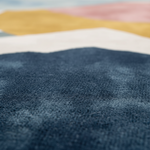Close-up of a textured blue rug with colorful abstract pattern in the background