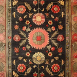 A beautifully hand-knotted area rug featuring a vintage Persian floral design. The rug displays intricate patterns with vibrant blooms in shades of pink, red, and yellow against a rich, dark background. Perfect for adding elegance to large living rooms, this rug combines traditional craftsmanship with a stunning aesthetic, ideal for those seeking floral or Persian rugs.