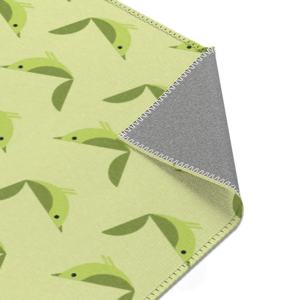 Serene songbird rug corner folded up, green birds on celery green with gray non-slip backing