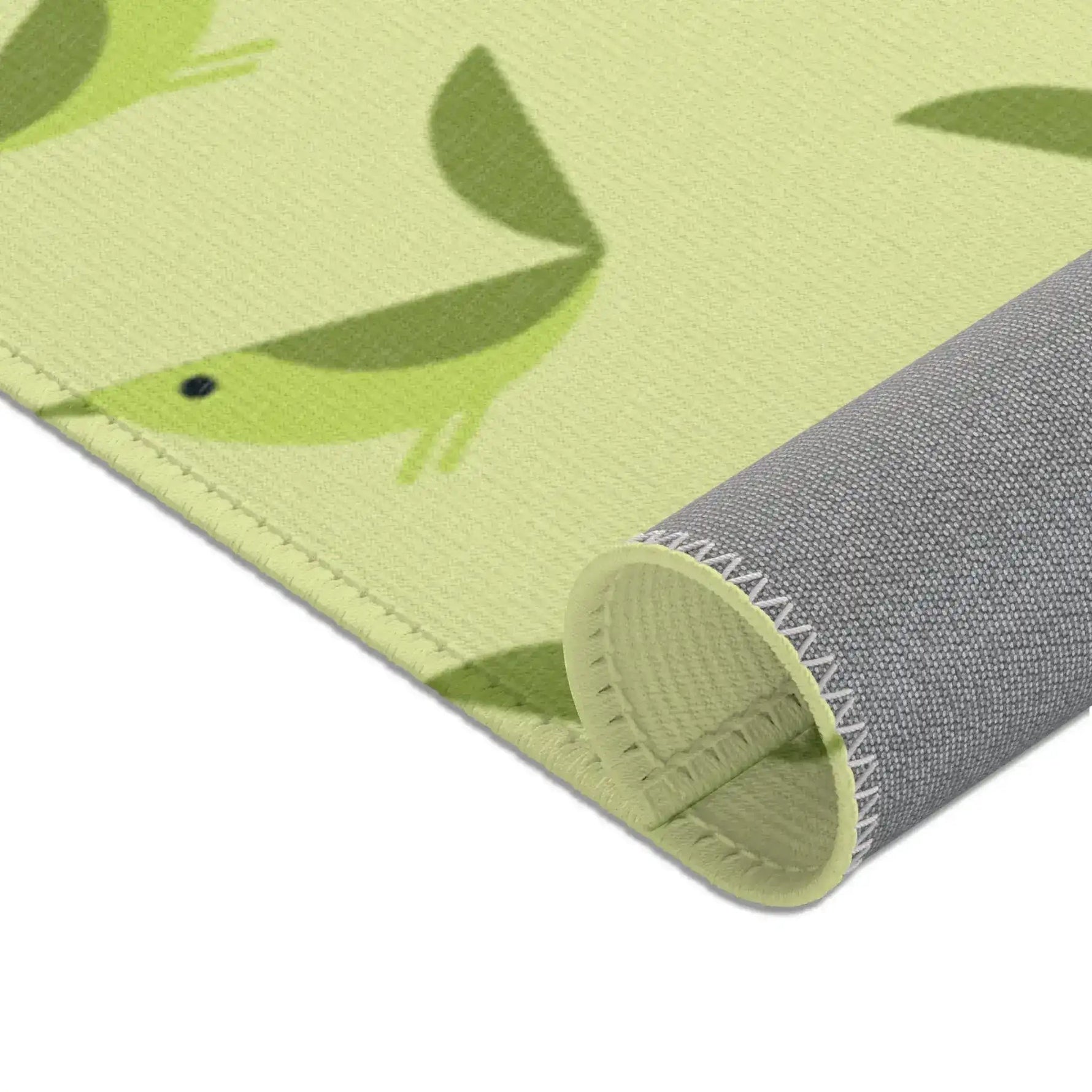Serene songbird rug corner rolled, single green bird close-up above gray fabric backing