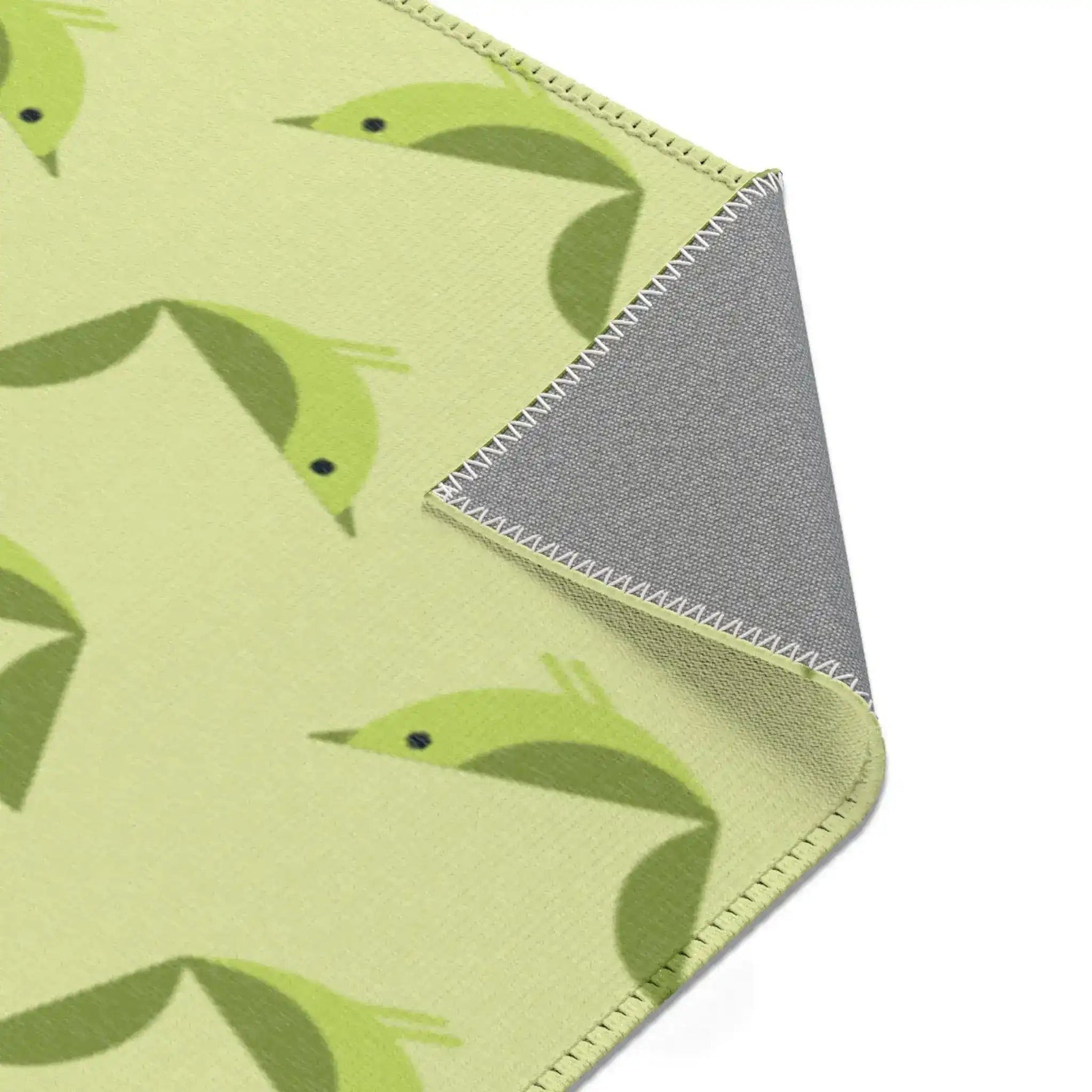 Serene songbird rug flipped corner showing green birds and gray underside with whipstitched trim