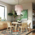 Elegant dining room featuring the Serenity Bloom Hand Knotted Area Rug, a beautiful floral rug with vintage Persian design. The large living room area rug adds a touch of sophistication under a modern dining table set, complemented by a chic chandelier and lush indoor plants.