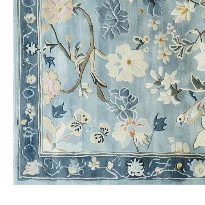 Close-up view of the Serenity Garden Hand Tufted Wool Area Rug, showcasing its intricate floral patterns in soft blues and creams. Perfect as a large living room rug, it adds a touch of elegance and warmth.