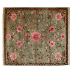 Explore the Serenity Valley Knotted Wool Rug, a stunning area rug perfect for enhancing your living room. This floral rug features intricate pink and red blossoms on a rich green background, bringing elegance and warmth to any space.