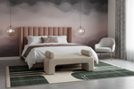 Modern bedroom with pink upholstered bed, white armchair, and geometric rug.