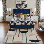 Modern bedroom with a blue upholstered bed, geometric-patterned bedding, and abstract art on the wall.
