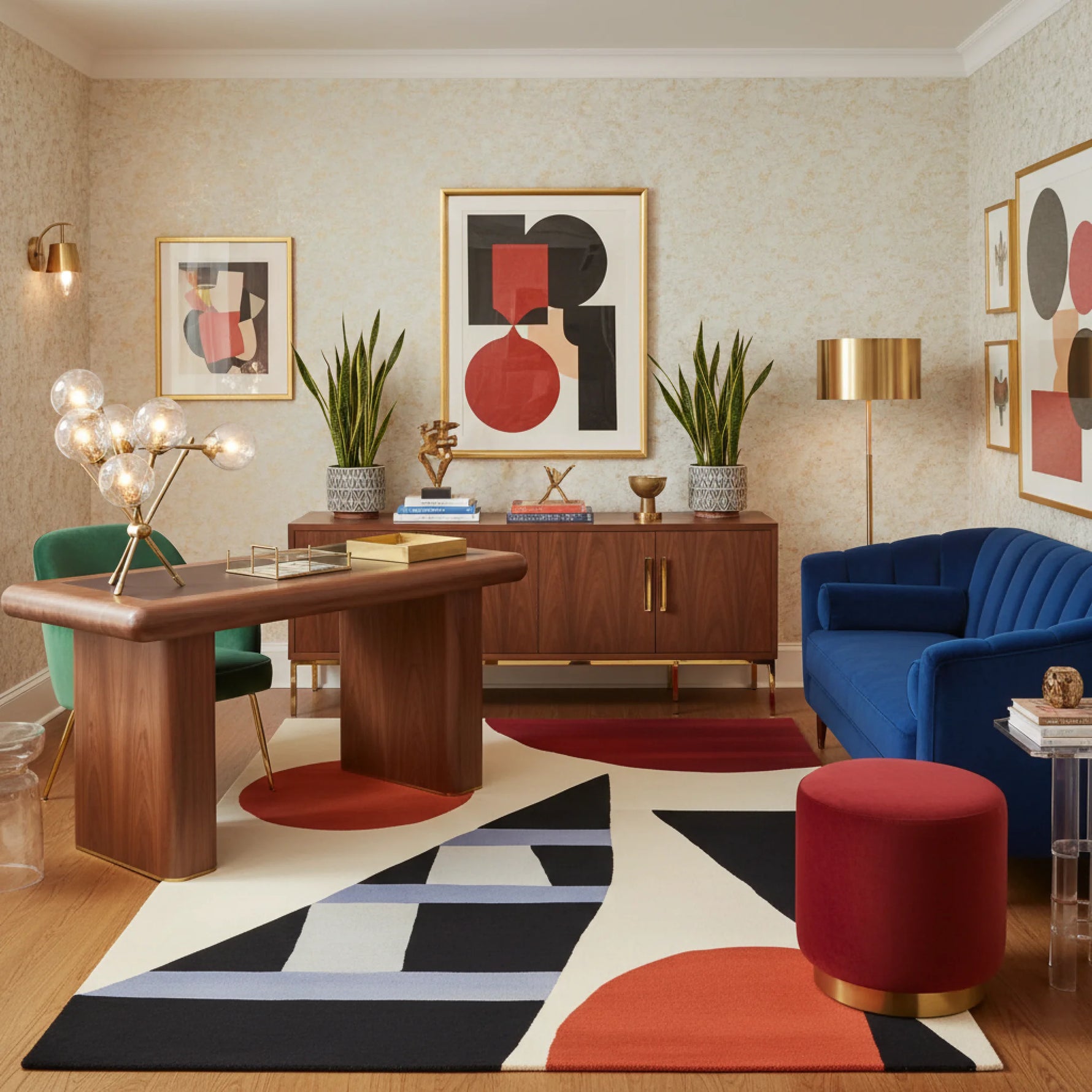 Modern living room with a wooden desk, blue sofa, a geometric wool rug, and abstract art on the walls.