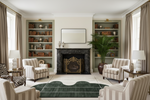 Luxurious living room with a fireplace, green knotted rug, bookshelves, and striped chairs.