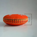 Round decorative throw pillow featuring bright orange fabric with intricate golden embroidery and red tassels, perfect for adding a pop of color to any home decor.