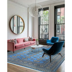 A stylish living room featuring a Sky Blue Anirudha Hand Knotted Area Rug. This elegant rug complements the modern decor with its intricate patterns, enhancing the living room area. The soft blue tones of the rug add a touch of sophistication, making it a perfect choice for those seeking rugs for living room spaces.