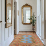 A stunning Sky Blue Java Kingdom Hand Knotted Area Rug gracefully adorns a bright hallway, reflecting elegance and style. This large living room rug features intricate patterns with a blend of blue and orange hues, perfect for enhancing any space. Ideal for those seeking rugs for living room, this piece adds a touch of sophistication and warmth to your home decor.