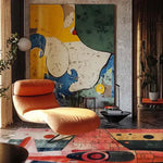 A vibrant contemporary area rug in a stylish living room, featuring abstract patterns with bold colors. This wool rug complements the modern decor, creating a striking contrast with the orange chaise lounge and large abstract wall art, making it an ideal choice for those seeking living room area rugs that stand out.