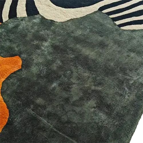 Close-up view of the Sleek Stripes Tufted Wool Rug, showcasing its bold, contemporary design with abstract patterns. The area rug features a blend of deep green, orange, and striped black and white colors, perfect for adding a modern touch to any dining room or office space.