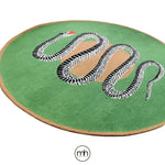 A vibrant round wool rug featuring an artistic design of a black and white snake on a lush green background, perfect for adding a bold statement to a dining room. This hand-tufted area rug combines style and functionality, ideal for formal dining room settings or as a striking centerpiece among large area rugs.