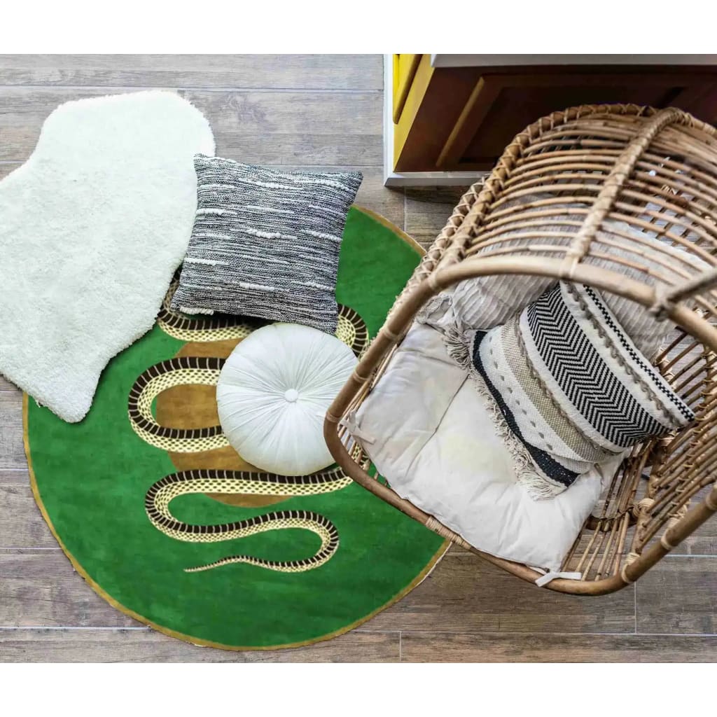 Top view of a vibrant green and gold round hand-tufted wool rug featuring a snake design, perfect for adding a touch of elegance to a dining room. The area rug complements the earthy tones of the surrounding decor, including a wicker chair and soft cushions, ideal for formal dining room settings.