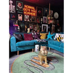 Stylish dining room featuring a vibrant Snake and Apple Green Gold Round Hand Tufted Wool Rug. This large area rug adds a bold touch to the formal dining room setting with its intricate snake design, complementing the eclectic decor and plush blue sectional sofa.