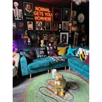 A vibrant living room featuring a round wool rug with a snake and apple design, ideal for adding a unique touch to a dining room. This large area rug complements the eclectic decor, including teal sofas and colorful cushions, creating a bold statement in formal dining room settings.