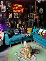 A vibrant living room featuring a round wool rug with a snake and apple design, ideal for adding a unique touch to a dining room. This large area rug complements the eclectic decor, including teal sofas and colorful cushions, creating a bold statement in formal dining room settings.