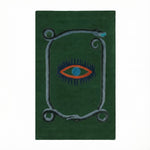 A striking green wool area rug featuring a unique design with a central red and blue eye motif, bordered by a snake pattern. This hand-tufted vintage rug is perfect for adding an artistic touch to your dining room, kitchen, or hallway. Ideal as a kitchen runner rug or bathroom runner rug, it complements formal dining room settings and adds warmth and style to any space.