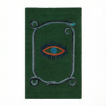 A striking green wool area rug featuring a unique design with a central red and blue eye motif, bordered by a snake pattern. This hand-tufted vintage rug is perfect for adding an artistic touch to your dining room, kitchen, or hallway. Ideal as a kitchen runner rug or bathroom runner rug, it complements formal dining room settings and adds warmth and style to any space.