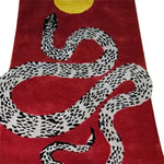 A vibrant red hand-tufted wool area rug featuring a striking black and white snake design coiled under a bright yellow sun. Perfect for adding a contemporary touch to living rooms, this 8x10 rug blends artistry with comfort, making it an ideal choice for those seeking stylish rugs for living room spaces.