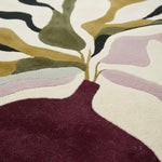 Close-up of a textured rug with abstract leaf design in various colors.