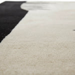 Close-up of a textured beige rug with a black section.