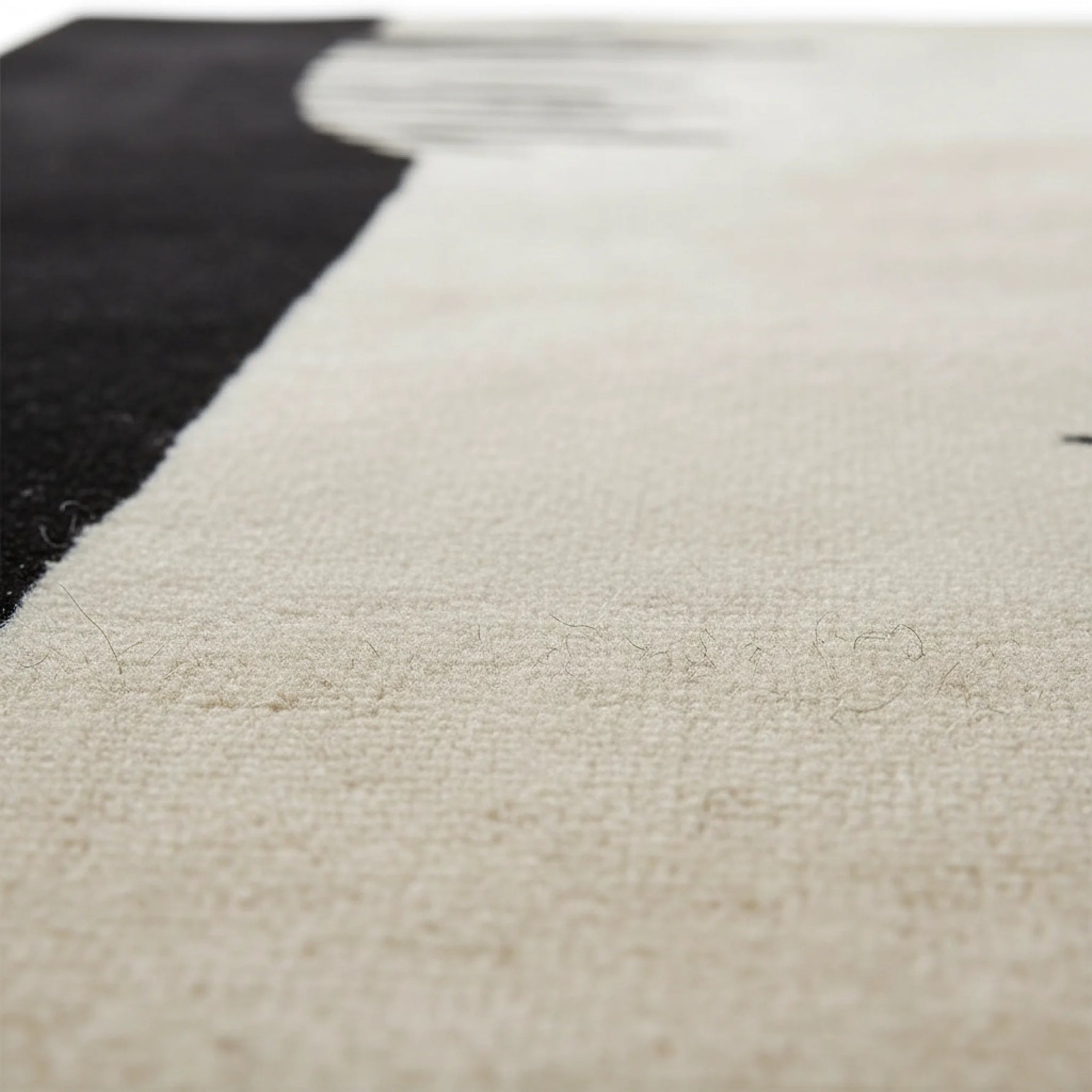 Close-up of a textured beige rug with a black section.