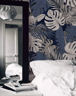 Soft pink blossoms and sage leaf wallpaper as bedroom feature wall behind white linen bedding and wood nightstand