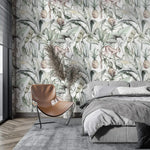 Soft watercolor tropical jungle wallpaper with palms and pineapples in bedroom with tan chair and grey bed