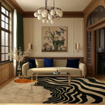 Elegant living room featuring the Solar Symphony Hand Tufted Rug, a contemporary wool area rug with striking black and white abstract patterns. Perfect as a dining table rug or for large living room spaces, this rug adds a modern touch to the decor, complemented by a cozy sofa and artistic wall decor.