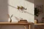 Solid brass rhino head wall hooks mounted above a wooden console with books and dried stems.