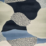 Close-up view of the Speckled Terrain Drift Hand Tufted Rug, showcasing its contemporary abstract design in shades of blue, black, and cream. This wool area rug features a unique speckled pattern, perfect for adding a modern touch to any living room.