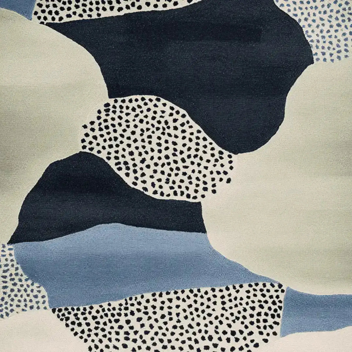 Close-up view of the Speckled Terrain Drift Hand Tufted Rug, showcasing its contemporary abstract design in shades of blue, black, and cream. This wool area rug features a unique speckled pattern, perfect for adding a modern touch to any living room.