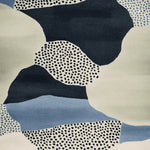 Close-up view of the Speckled Terrain Drift Hand Tufted Rug, showcasing its contemporary abstract design in shades of blue, black, and cream. This wool area rug features a unique speckled pattern, perfect for adding a modern touch to any living room.