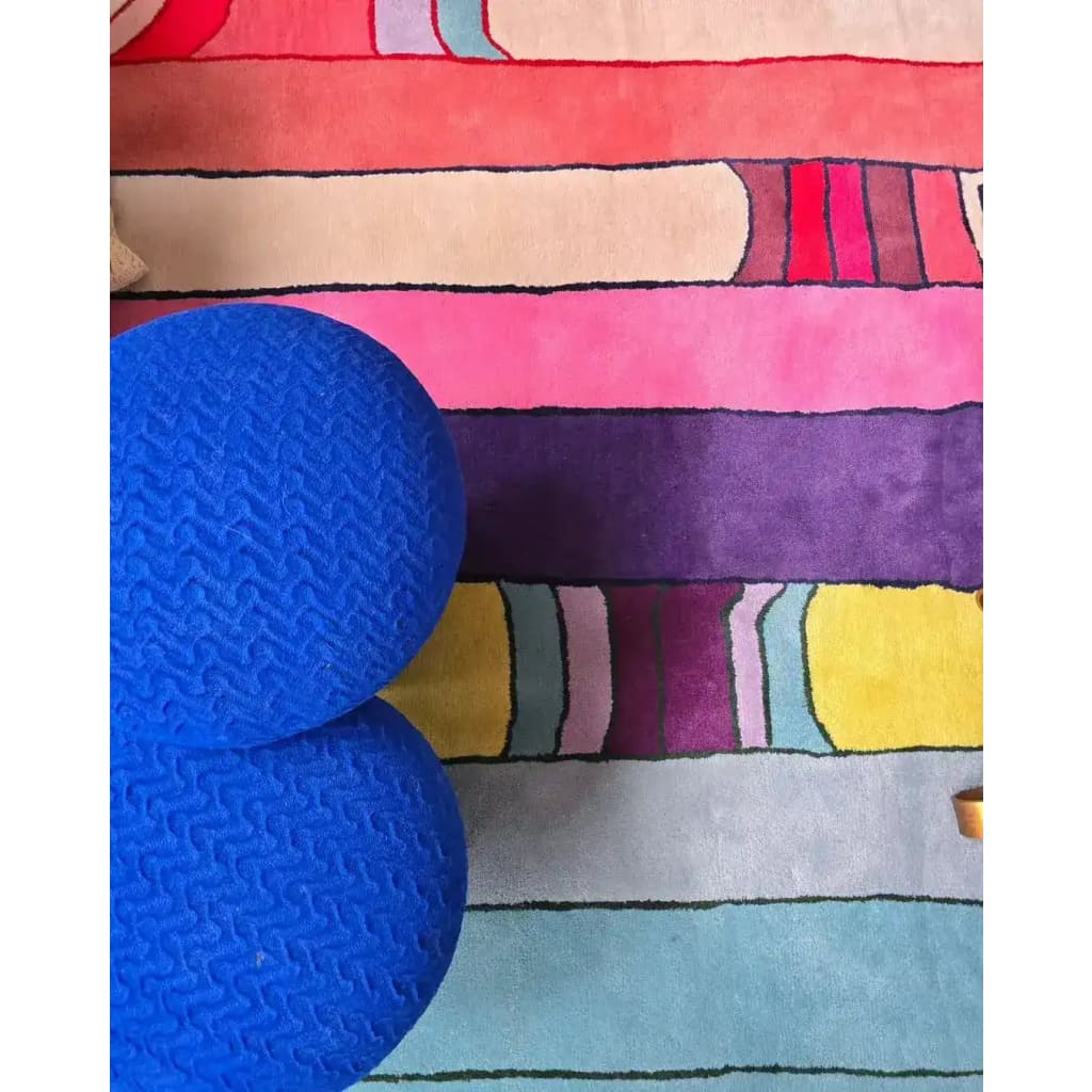 A vibrant Spectrum Stripe Hand Tufted Area Rug, ideal for large living rooms. This contemporary wool rug in an 8x10 size features bold, colorful stripes in shades of pink, purple, yellow, and blue, providing a lively touch to modern living room decor.