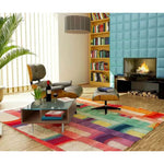 A vibrant Spectrum Stripe Hand Tufted Area Rug in an 8x10 size elegantly enhances a contemporary living room setting. The large wool rug features bold, colorful stripes, adding a modern touch to the space. Positioned in front of a cozy fireplace, it complements the stylish furniture and decor, making it an ideal choice for large living room rugs.