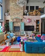 A vibrant Spectrum Stripe Hand Tufted Rug in a cozy living room setting. This contemporary wool area rug adds a splash of color with its bold, geometric pattern, making it an ideal choice for large living room rugs or those seeking living room rugs 8x10. The rug complements the eclectic decor, featuring a mix of modern and vintage elements, creating a warm and inviting atmosphere.